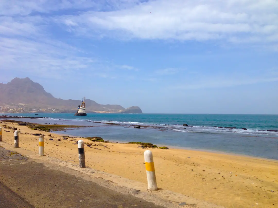 Coastal road along a sandy beach near Mindelo with a shipwreck offshore
